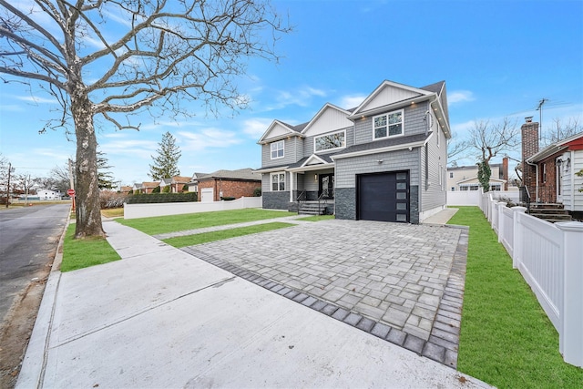 view of front of house featuring stone siding, decorative driveway, a front lawn, and fence