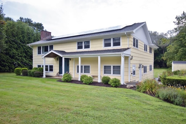 view of front of home featuring solar panels, a chimney, and a front yard