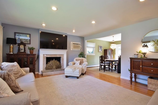 living area with baseboard heating, recessed lighting, wood finished floors, and a wall mounted air conditioner