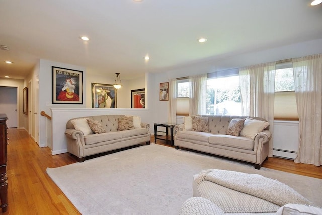 living room with a healthy amount of sunlight, a baseboard heating unit, and light wood-style flooring