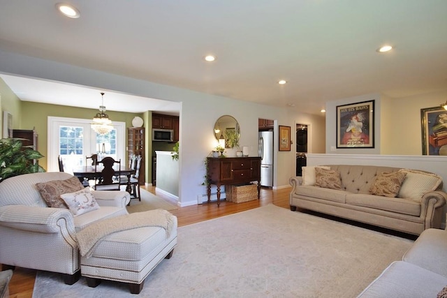 living room featuring recessed lighting, a baseboard heating unit, baseboards, and light wood finished floors