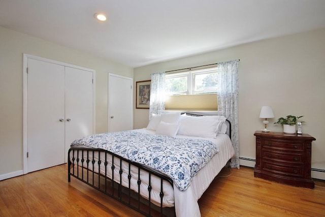 bedroom featuring a baseboard heating unit, light wood-type flooring, and a closet