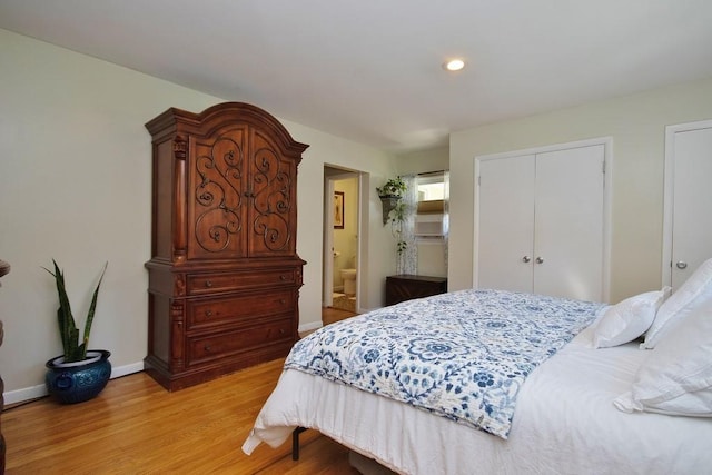 bedroom featuring baseboards, recessed lighting, light wood-style floors, two closets, and connected bathroom