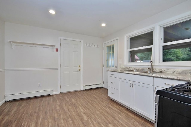 kitchen featuring white cabinetry, light stone countertops, light wood finished floors, and a baseboard radiator