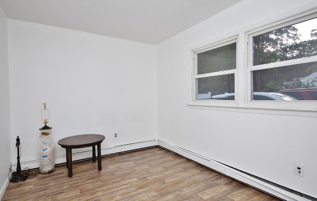 unfurnished room with baseboard heating and wood finished floors