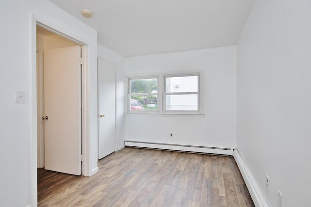 spare room featuring baseboard heating and wood finished floors