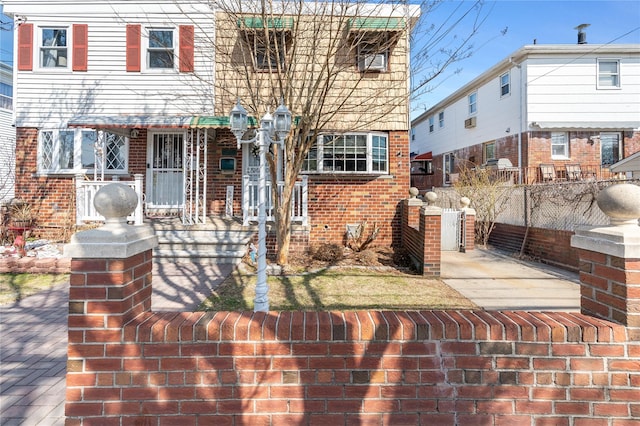view of front of property featuring brick siding and fence