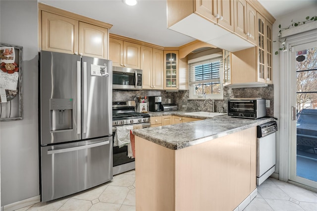 kitchen featuring a toaster, stainless steel appliances, tasteful backsplash, a sink, and light brown cabinetry