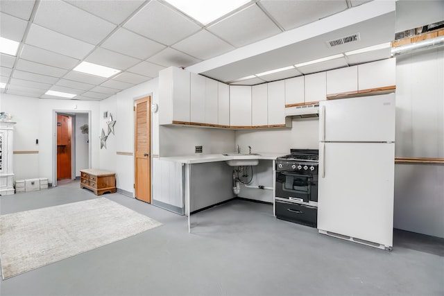 kitchen featuring light countertops, finished concrete flooring, under cabinet range hood, high end stove, and freestanding refrigerator