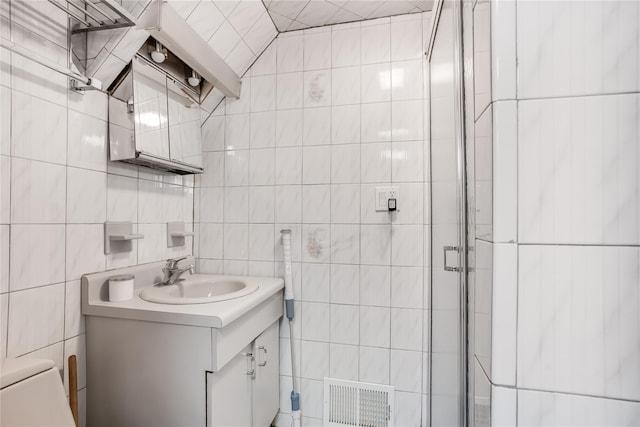 full bathroom with vanity, a shower stall, tile walls, and visible vents