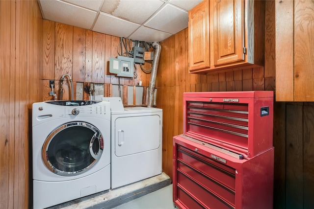 laundry room featuring cabinet space, independent washer and dryer, and wood walls