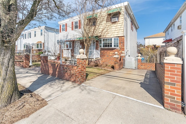 view of front of home featuring fence, driveway, a gate, brick siding, and a porch