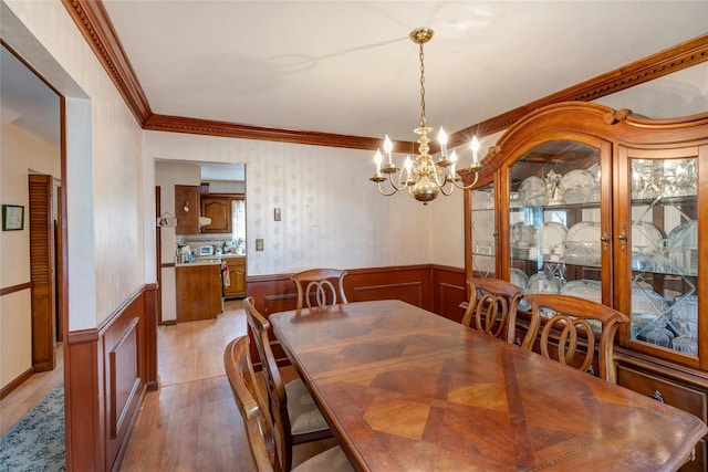 101 Grissom Way, Hauppauge, NY 11788 - dining area featuring a notable chandelier, ornamental molding, a wainscoted wall, a decorative wall, and light wood finished floors