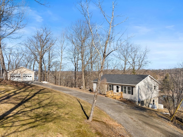 view of front facade with a front yard, dirt driveway, and a shingled roof