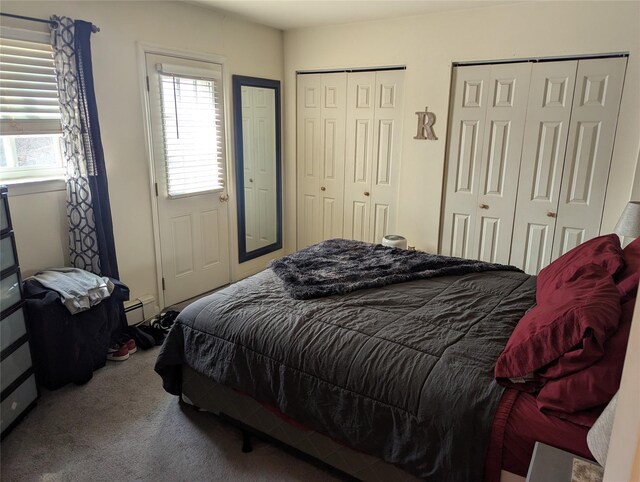 bedroom with a baseboard heating unit, two closets, and carpet flooring