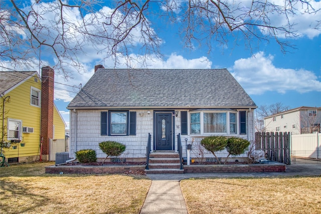 bungalow-style home featuring a shingled roof, a front yard, and fence