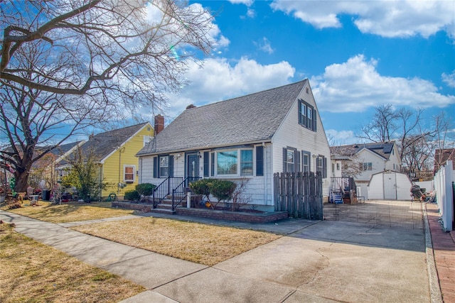 view of front of property with an outbuilding, a chimney, a front lawn, and a shingled roof