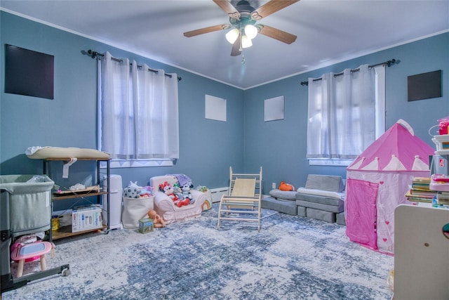 game room with ceiling fan, baseboard heating, ornamental molding, and carpet