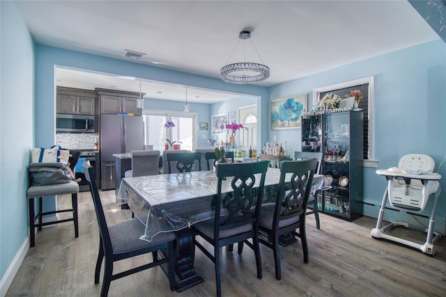 dining room featuring visible vents, baseboards, and wood finished floors