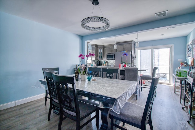 dining space with wood finished floors, visible vents, and baseboards