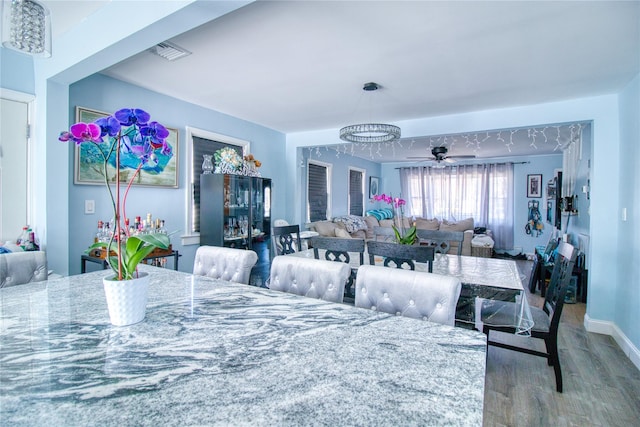 dining area with a ceiling fan, wood finished floors, visible vents, and baseboards