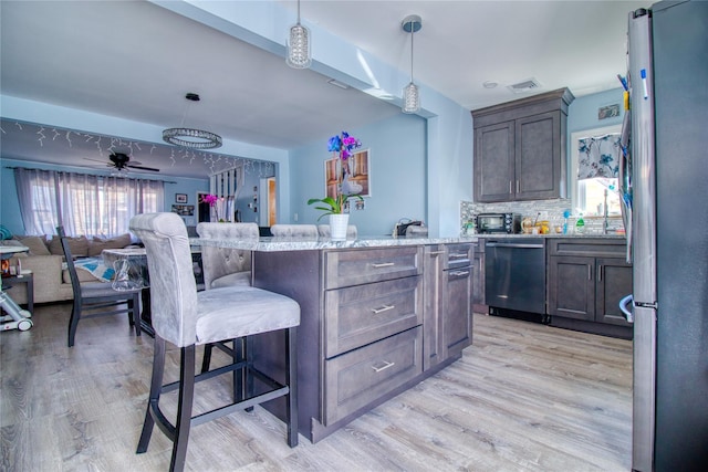 kitchen with light wood-style flooring, dishwasher, a breakfast bar, and freestanding refrigerator