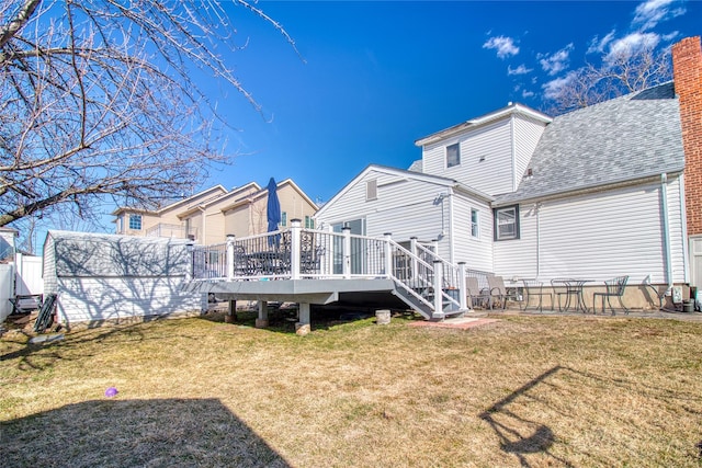 rear view of property featuring a yard, a wooden deck, and a shingled roof