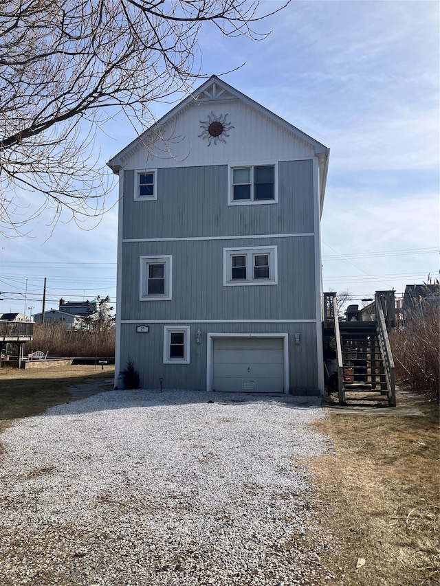 back of property featuring gravel driveway and stairs