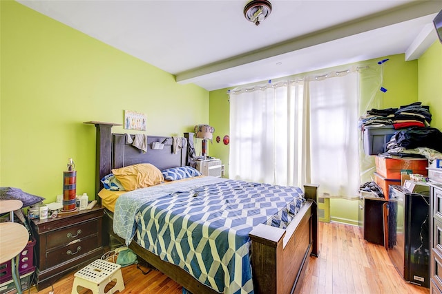 bedroom featuring beam ceiling and wood finished floors