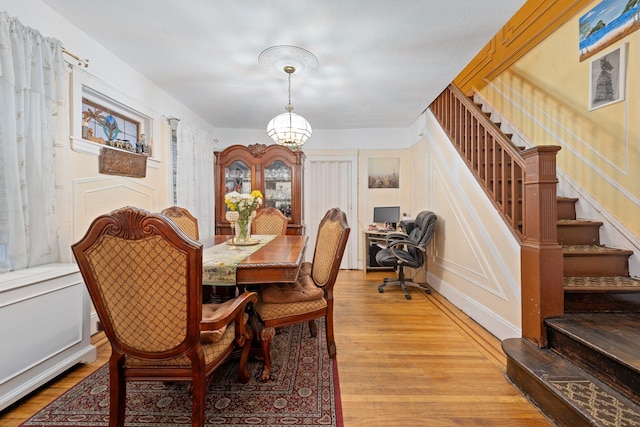 dining space with a notable chandelier, stairway, and light wood-style flooring