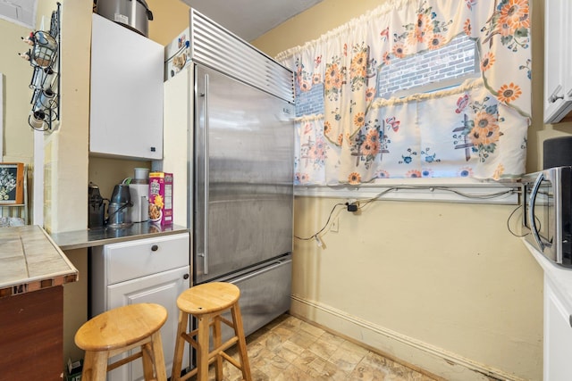 kitchen with baseboards, white cabinetry, stainless steel countertops, and stainless steel appliances