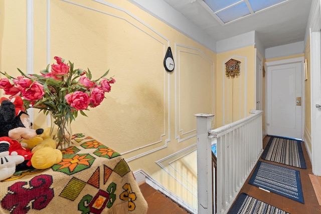 hall with wood finished floors and an upstairs landing