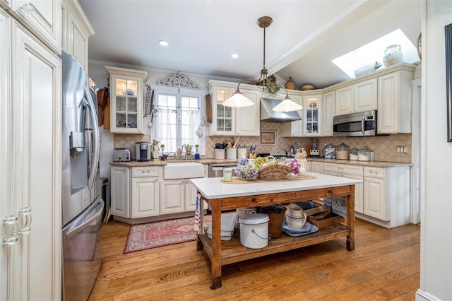 kitchen with a sink, extractor fan, light wood-type flooring, and stainless steel appliances