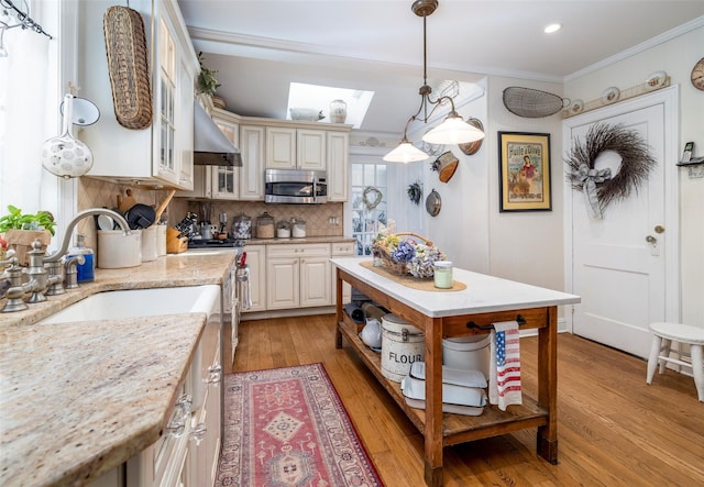 kitchen with light wood finished floors, crown molding, decorative backsplash, stainless steel appliances, and open shelves