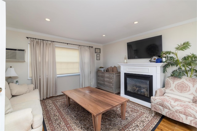 living room featuring a glass covered fireplace, crown molding, light wood-style flooring, and a wall mounted air conditioner