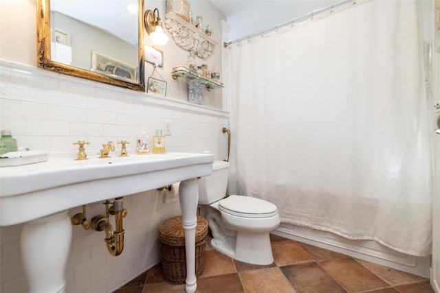 full bath with tile walls, toilet, a wainscoted wall, and shower / tub combo with curtain