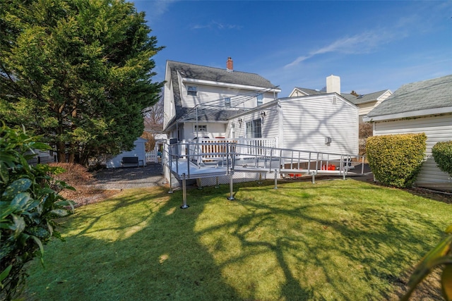 rear view of property with a deck, a chimney, and a yard