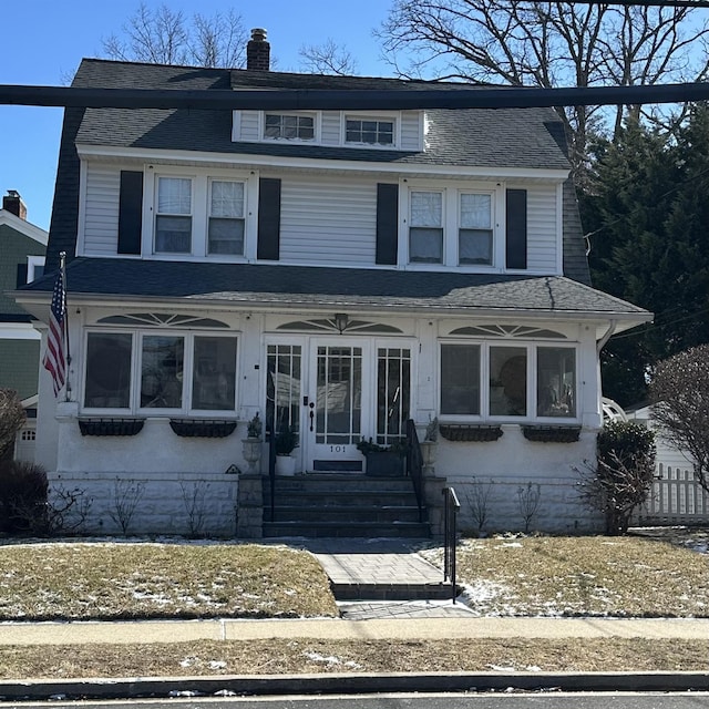 traditional style home featuring a chimney and a shingled roof