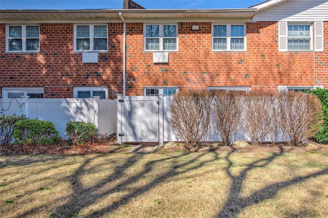 back of house featuring a yard, fence, and brick siding