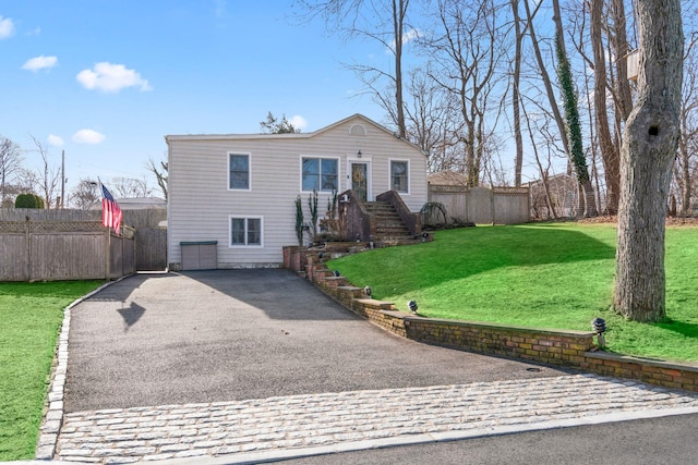 view of front of home with a front lawn, an attached garage, fence, and aphalt driveway