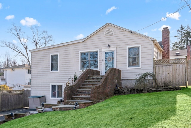 back of property with a lawn and fence