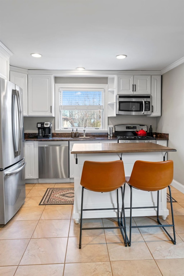 kitchen with dark countertops, appliances with stainless steel finishes, white cabinets, and a breakfast bar