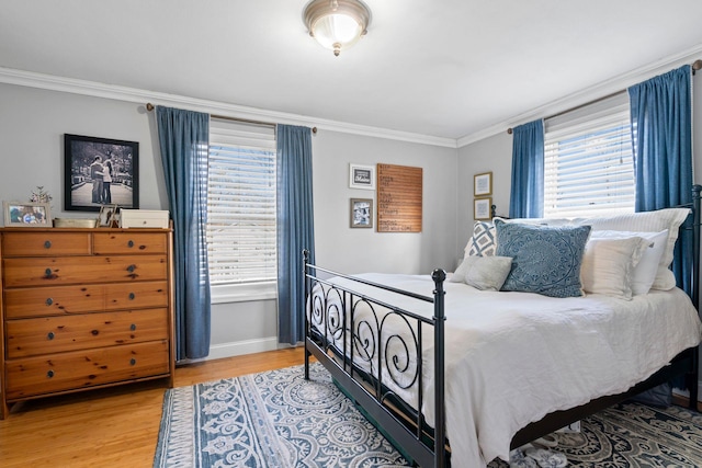 bedroom with light wood-style flooring, crown molding, and baseboards