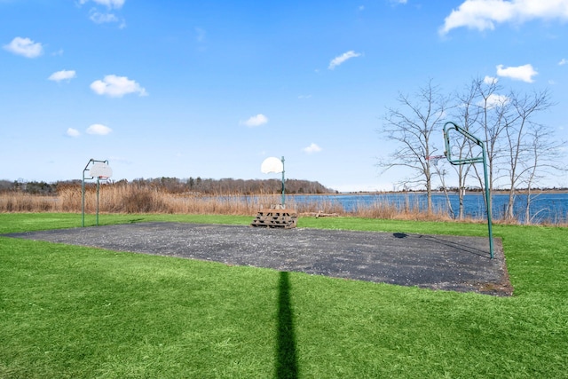 exterior space with a lawn, community basketball court, and a water view