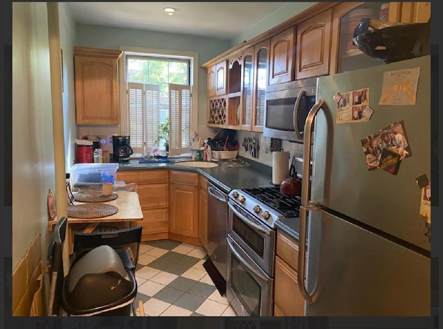 kitchen with a sink, decorative backsplash, dark countertops, and appliances with stainless steel finishes