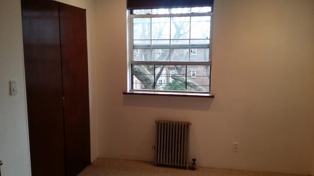 unfurnished bedroom featuring carpet flooring and radiator heating unit