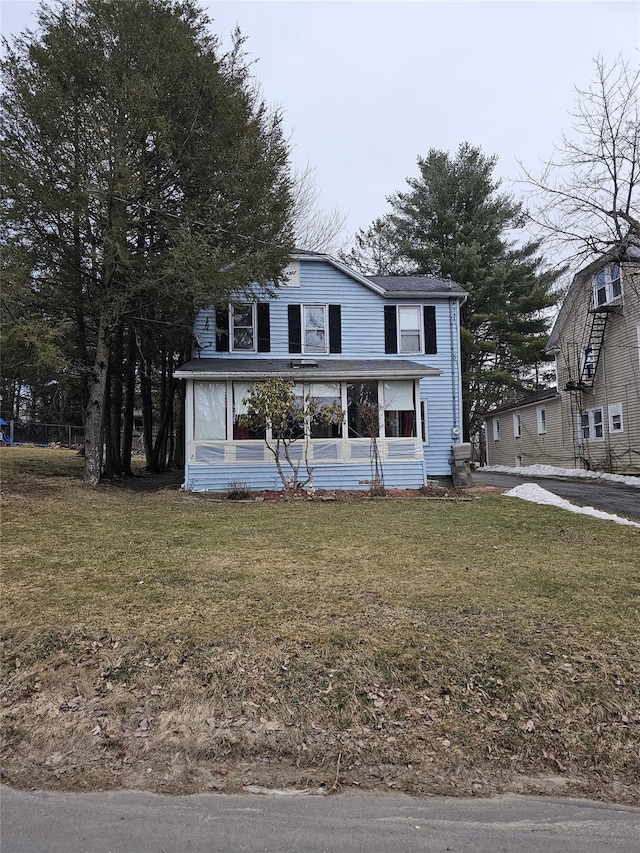 view of front of property featuring a front lawn and a sunroom