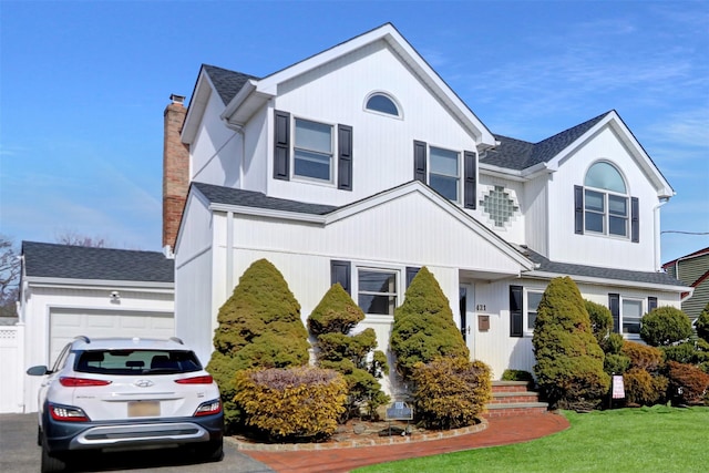 view of front of house with a garage, a front yard, and a chimney