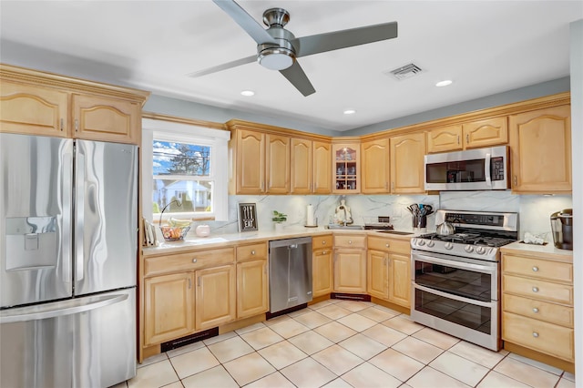 kitchen with light brown cabinetry, backsplash, appliances with stainless steel finishes, light countertops, and ceiling fan