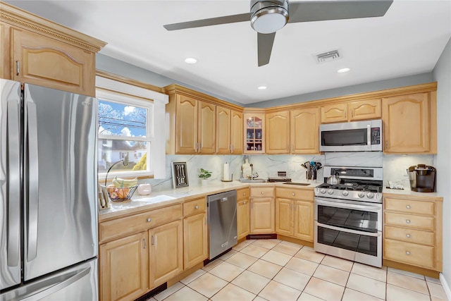 kitchen featuring visible vents, light brown cabinetry, stainless steel appliances, light countertops, and tasteful backsplash